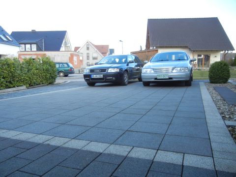 1999 Ford Fairlane - Two sedans are parked in a paved driveway in front of houses.
