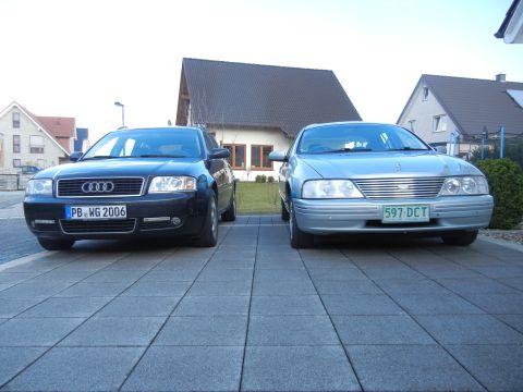 1999 Ford Fairlane - Two cars, an Audi and a silver sedan, are parked side-by-side on a paved driveway.