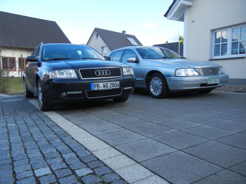 1999 Ford Fairlane - Two cars are parked in a driveway. The silver car is a Ford sedan and the black car is an Audi wagon.