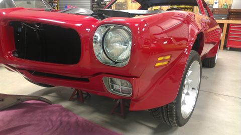 1972 Pontiac Trans Am - A red muscle car is shown from the front, elevated on jack stands in a workshop setting.