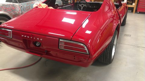 1972 Pontiac Trans Am - A red Pontiac Firebird is partially restored, with its rear end visible and the "PONTIAC" name clearly displayed.