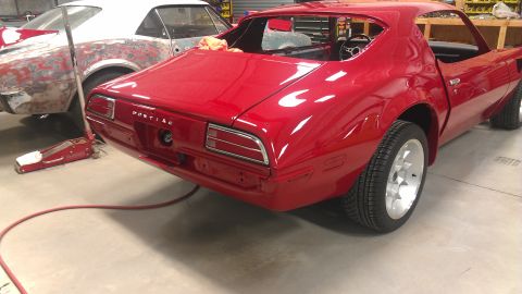 1972 Pontiac Trans Am - Two cars are in a garage, one red Pontiac Firebird and another car being prepped for paint.