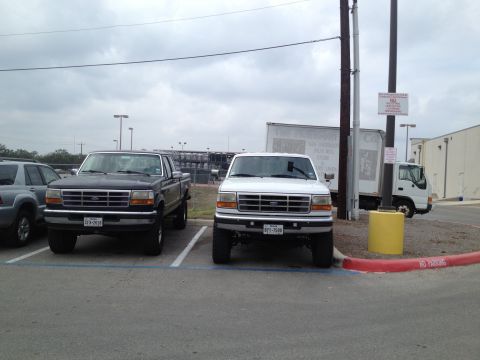 1997 Ford F-350 - Two Ford F-350 trucks are parked in a lot under an overcast sky.