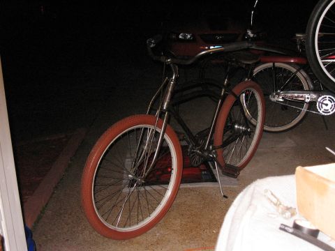Bicycle with red tires and chrome handlebars parked in front of a red vehicle