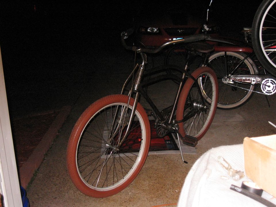 Bicycle with red tires and chrome handlebars parked in front of a red vehicle