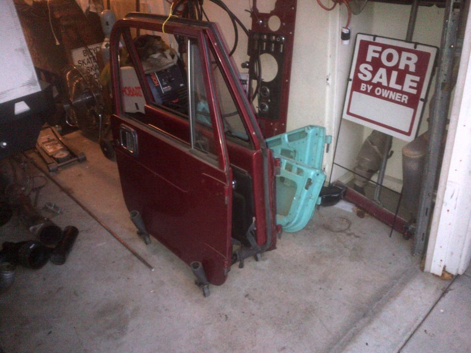 Red Jeep CJ doors and a blue door in a garage with a 'For Sale' sign