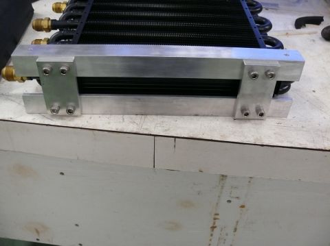 1976 Chevrolet Corvette - Aftermarket oil cooler assembly with aluminum brackets and brass fittings shown on a workbench.