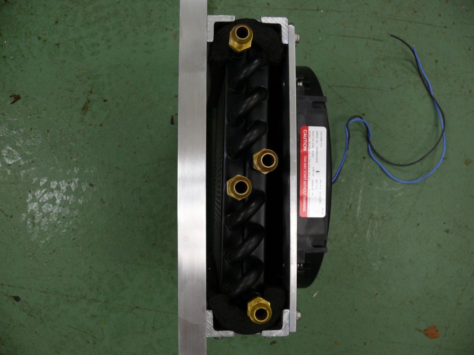 Oil cooler with fan and brass fittings, mounted on a green surface