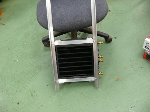 Oil cooler assembly with black fins and brass fittings, mounted in an aluminum frame