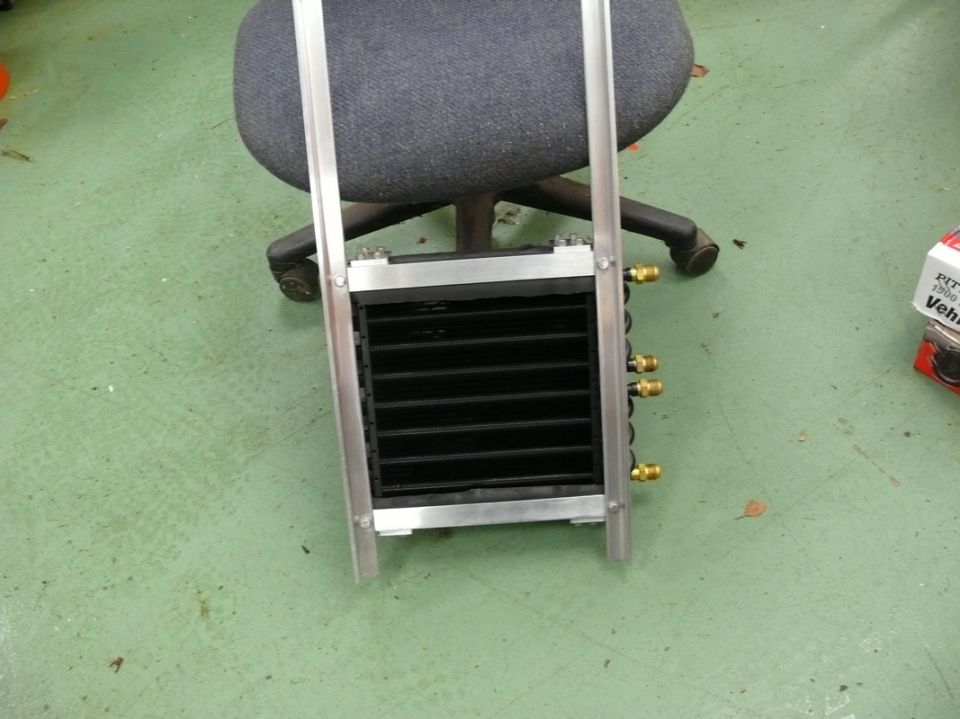 Oil cooler assembly with black fins and brass fittings, mounted in an aluminum frame