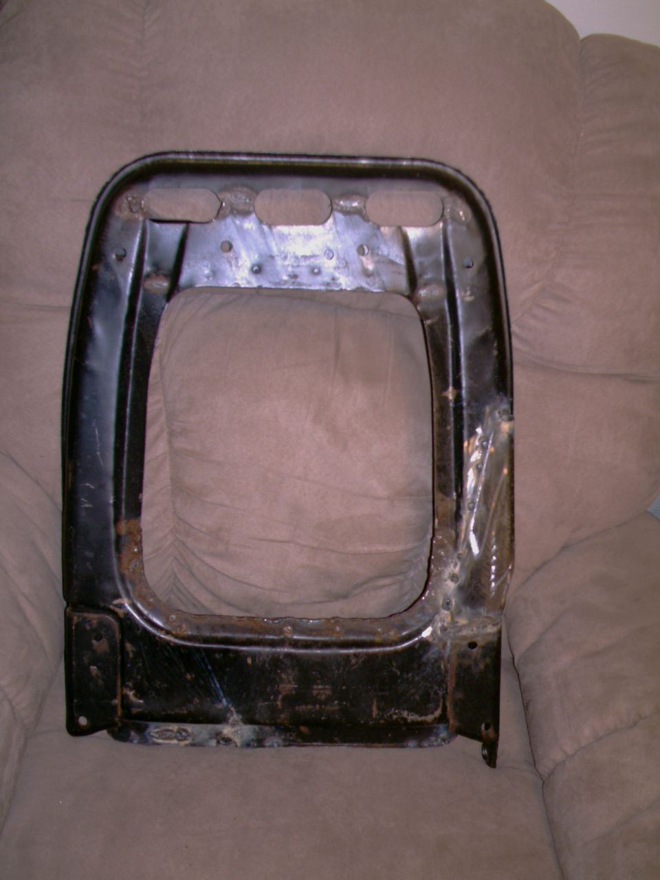 Black metal seat frame with holes along the top edge, resting on a couch