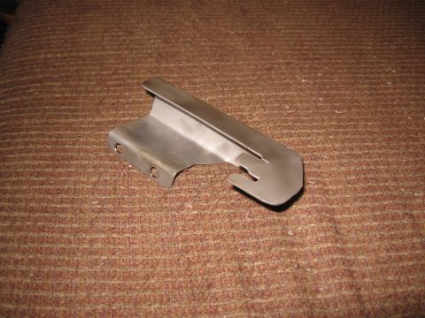Metal bracket with two holes and a slot on a brown textured surface