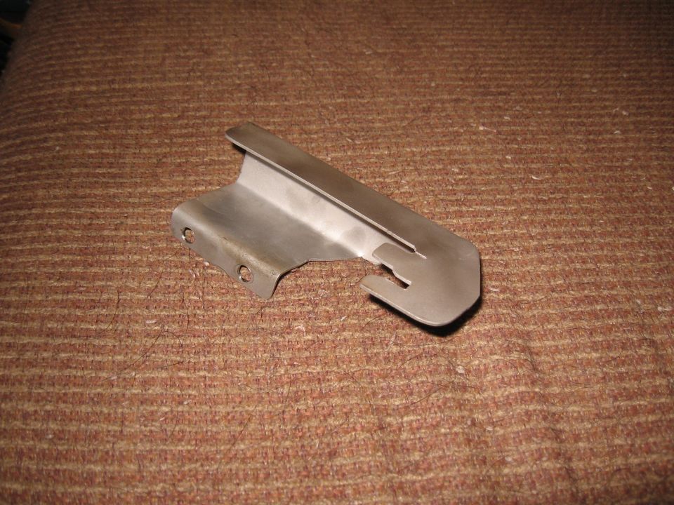 Metal bracket with two holes and a slot on a brown textured surface