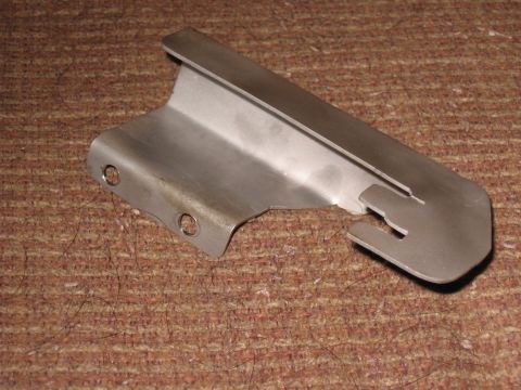 Brushed metal bracket with two mounting holes and a notched end on a brown textured surface.