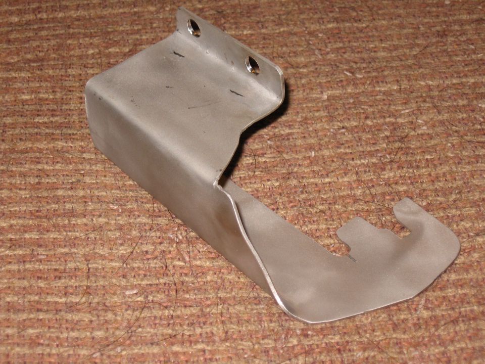 Metal bracket with a hook, resting on a textured surface