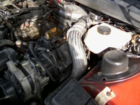 1999 Mercury Grand Marquis - Close-up view of a vehicle's engine compartment, showing various components like the alternator and coolant reservoir.