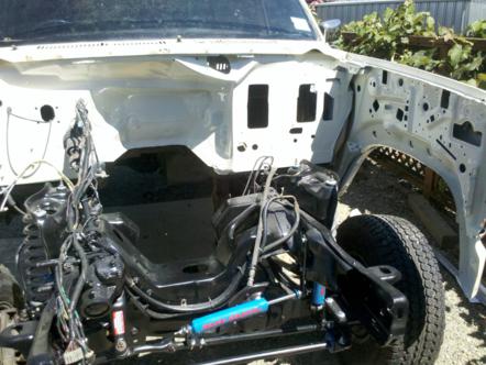 1982 Ford Bronco - The engine bay of a 1982 Ford Bronco, showing the chassis, wiring, and a blue shock absorber.