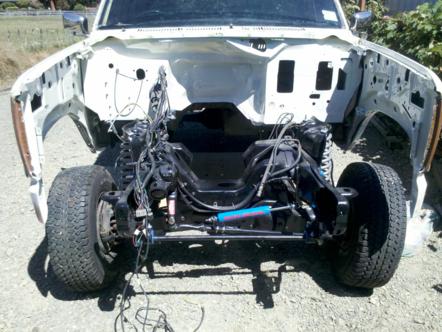 1982 Ford Bronco - The front end of a vehicle is shown with the engine bay disassembled, revealing the chassis and suspension.