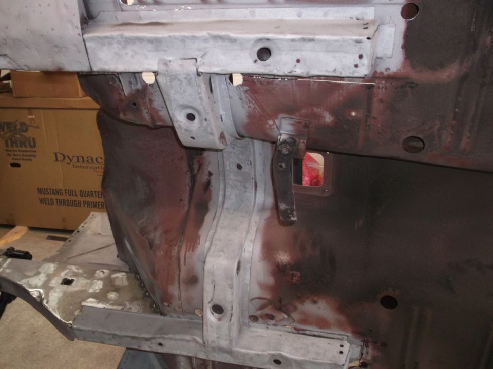 Car frame section with rust and primer, showing mounting points