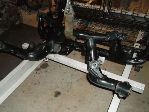 1967 Ford Mustang - Car frame components are suspended and supported by a stand, with a visible seat structure behind.