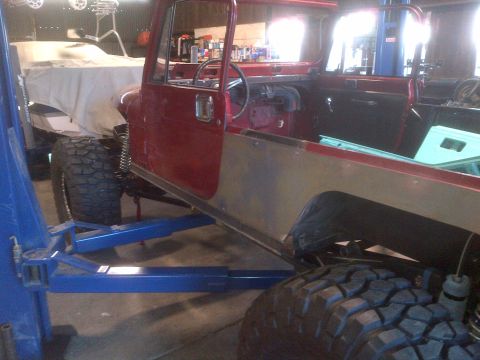 1985 Jeep CJ7 - 1985 Jeep CJ7 body being worked on in a garage, lifted for repairs or modifications.