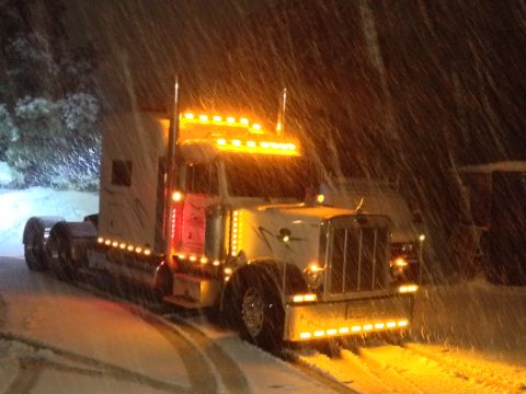 2003 Peterbilt 379 - A Peterbilt truck is seen driving through a snowy landscape at night, its numerous lights illuminating the falling snow.