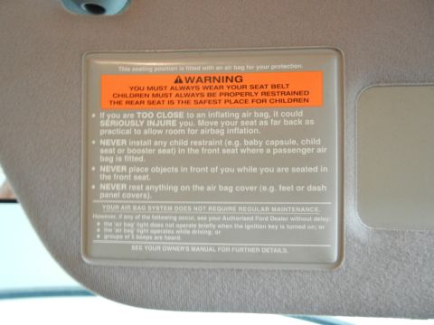 1999 Ford Fairlane - This image shows a sun visor with a detailed warning label about air bag safety and proper seating.