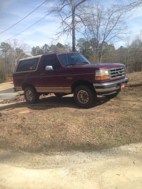 1996 Ford Bronco - Maroon 1996 Ford Bronco with a tan removable top is parked outdoors.