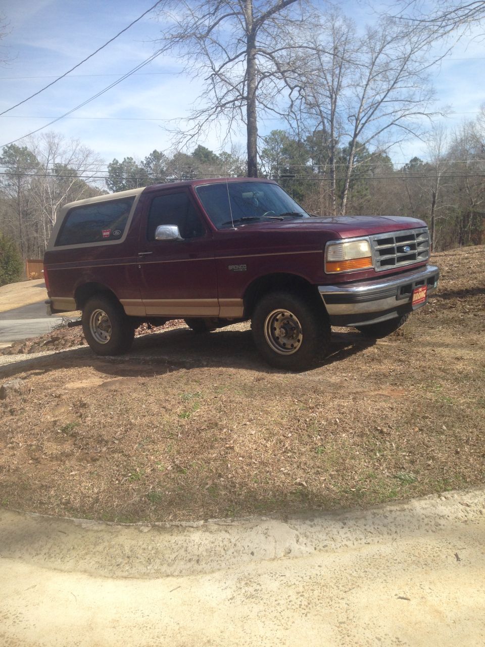 1996 Ford Bronco parked on a dirt lot, side and front view