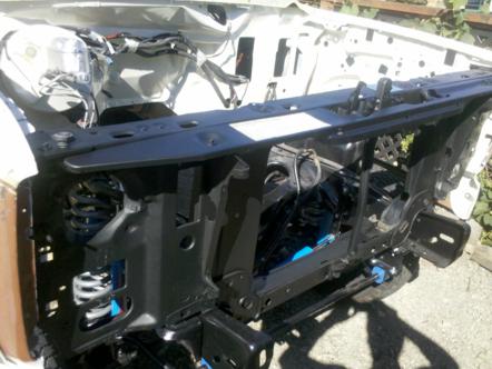 1982 Ford Bronco - The engine bay of a white vehicle is shown with exposed components and black structural elements.