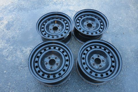 2001 Ford Crown Victoria - Set of four steel wheels, likely for a sedan or similar vehicle, shown on a wet surface.