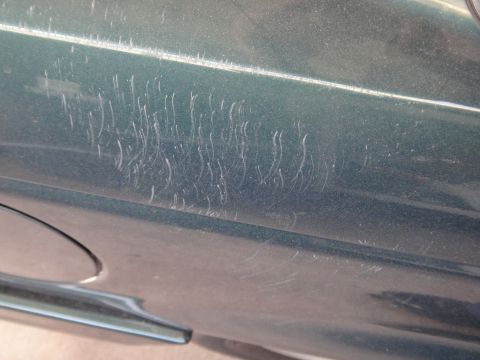 1993 Ford Taurus - This photo shows numerous light scratches on the lower portion of a vehicle's door panel.