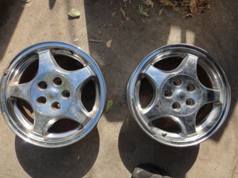 1993 Ford Taurus - A pair of chrome alloy wheels are displayed on a concrete surface, likely for sale.