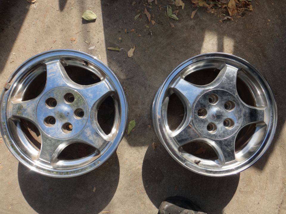 Two chrome alloy wheels with five spokes on concrete