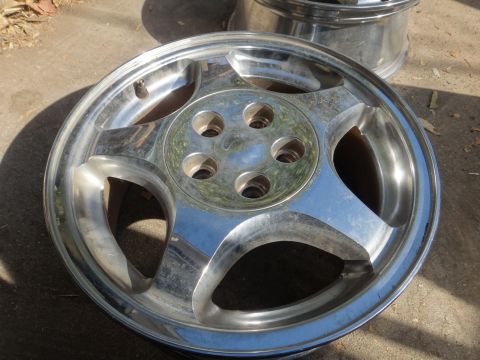 1993 Ford Taurus - A single chrome alloy wheel is shown, resting on a concrete surface with some leaves nearby.