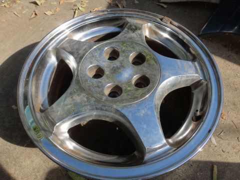1993 Ford Taurus - Chrome wheel shown up close, resting on the ground.