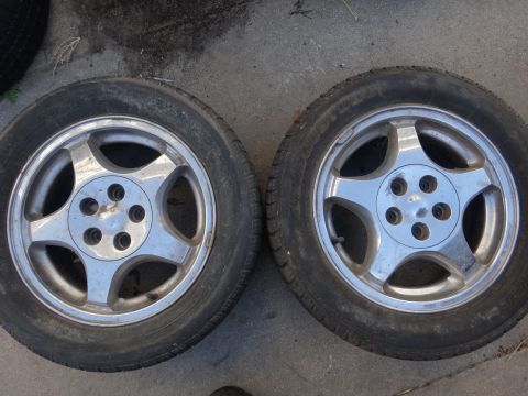 1993 Ford Taurus - Two alloy wheels with tires are shown from a top-down perspective on a concrete surface.