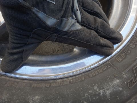 1993 Ford Taurus - Close-up of a gloved hand on a tire rim, showing part of the tire's sidewall markings.