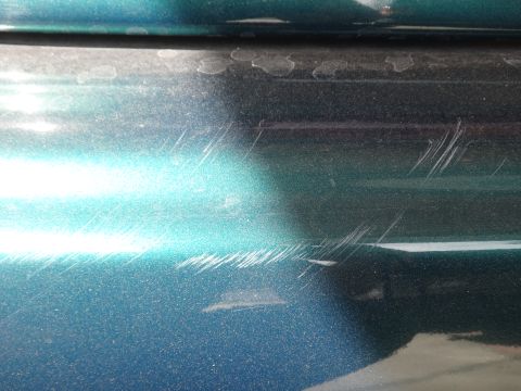 1993 Ford Taurus - The teal paint on this car door has numerous scratches and scuff marks.