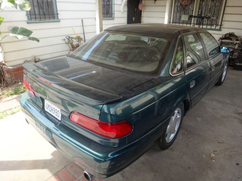 1993 Ford Taurus - Rear view of a dark green sedan with a spoiler, showing its license plate and taillights.