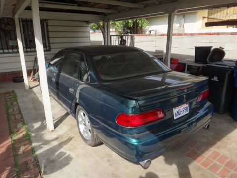 1993 Ford Taurus - Rear view of a dark green 1993 Ford Taurus sedan parked under a carport.