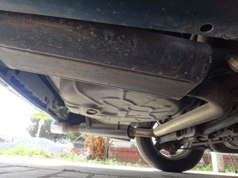 1993 Ford Taurus - The underside of a vehicle reveals its exhaust pipes, fuel tank, and suspension components.