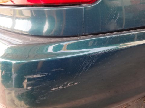 1993 Ford Taurus - Rear bumper shows significant damage from scratches and impacts.