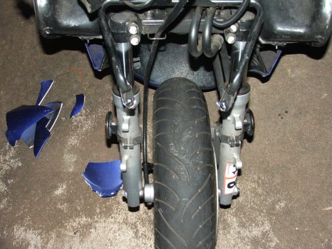 2006 Honda Reflex - The front end of a motorcycle shows damage, with broken blue fairing pieces on the ground.