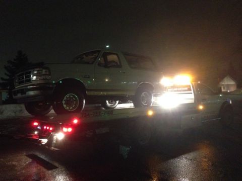 1995 Ford Bronco - Ford Bronco being towed at night, with the tow truck's emergency lights illuminated.