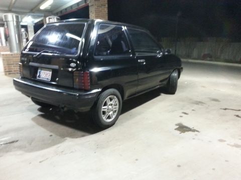 1991 Ford Festiva - Rear view of a black 1991 Ford Festiva parked outdoors at night.