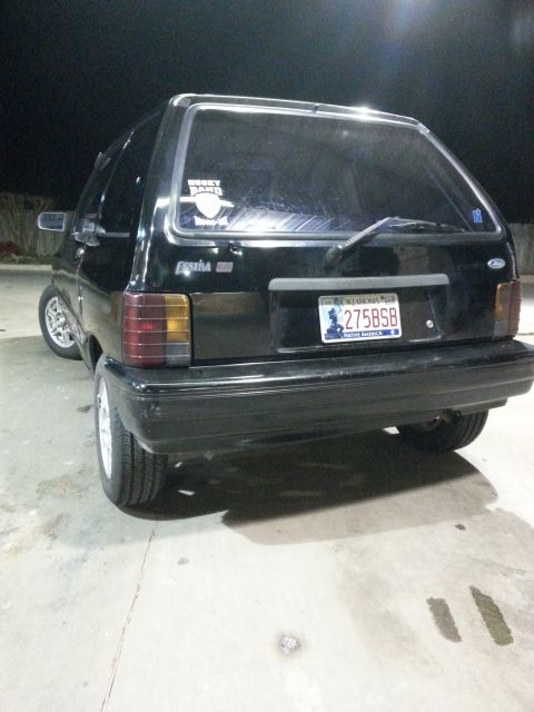 1991 Ford Festiva - This black 1991 Ford Festiva hatchback is viewed from the rear, showing its taillights and license plate.