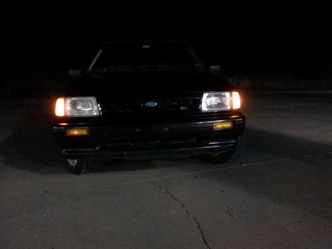 1991 Ford Festiva - Front view of a black 1991 Ford Festiva parked at night.