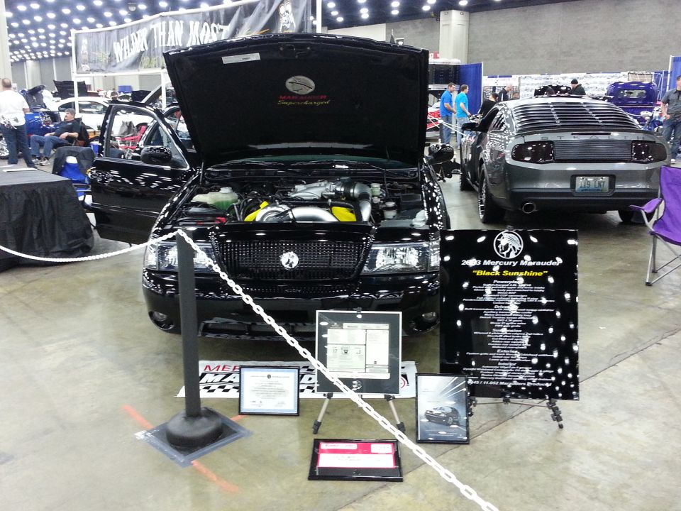 Black 2003 Mercury Marauder with hood open, showing engine bay. Another car is parked behind it
