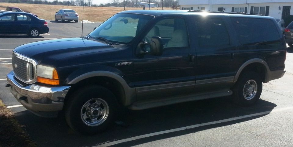 Dark blue Ford Excursion parked in a lot. It has a chrome grille and bumper